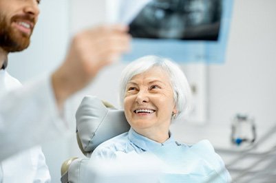 Dentist reviewing patient’s X-ray while she smiles