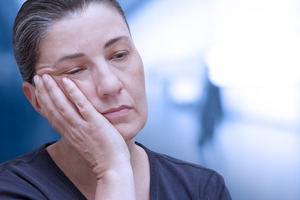 Tired woman with anemia rubbing her jaw